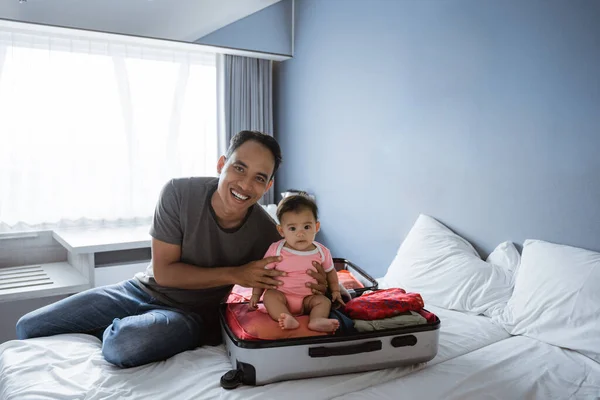 Pai sentado segurar um bebê e sorrindo ao olhar para a câmera — Fotografia de Stock