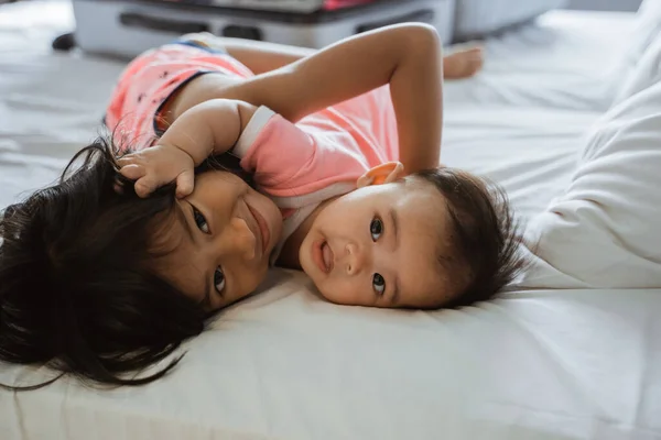 Dvě děti objímají, když leží na posteli — Stock fotografie