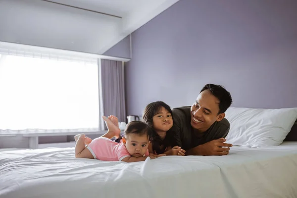 Padre e i due bambini sdraiati sul letto — Foto Stock
