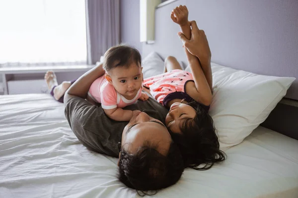 Père asiatique étreint les deux enfants couchés dans le lit — Photo