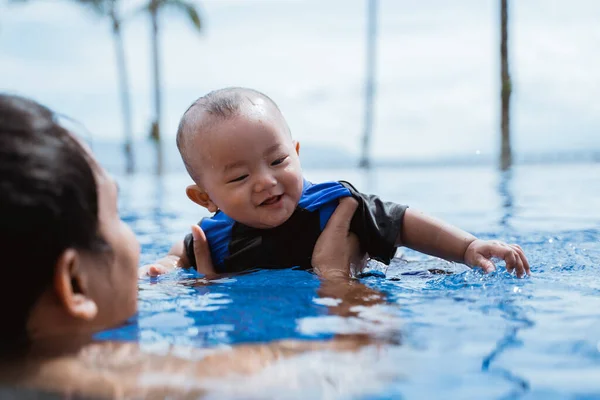 Papa tient son bébé tout en jouant dans la piscine — Photo