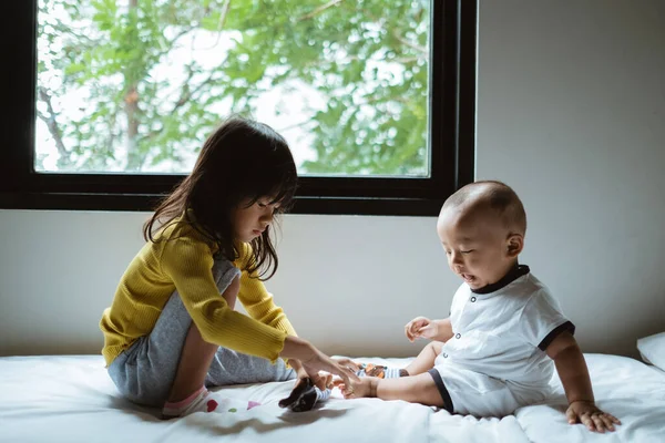 ベッドの上で兄弟姉妹の交流を — ストック写真