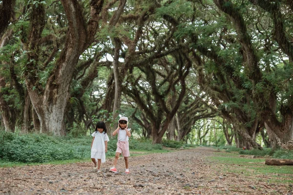 2人の子供が日陰の木の間を — ストック写真