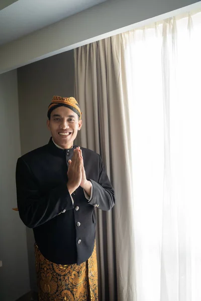 Asiatico uomo indossare tradizionale abiti di indonesiano beskap con benvenuto gesto — Foto Stock
