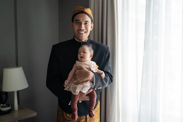 Aziatische man draagt traditionele kleren van Indonesische beskap met het dragen van kleine dochter — Stockfoto