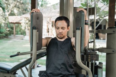 Asyalı genç adam göğüs egzersizi yapıyor.