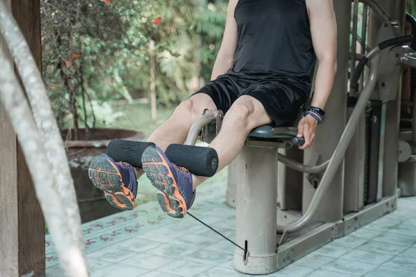 Asiatischer Mann trainiert mit Beinstreckmaschine — Stockfoto
