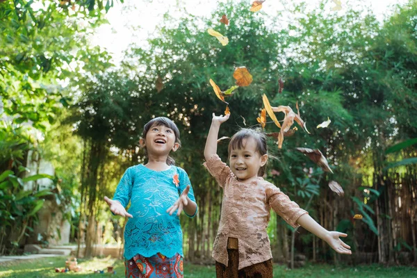 Dwie ładne dziewczyny w tradycyjnej kebaya javanese gra suszone liście — Zdjęcie stockowe