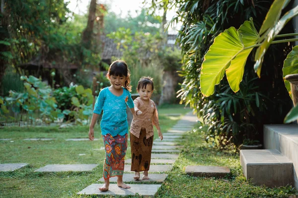 Twee mooie meisje dragen traditionele Javaanse kebaya met hand in hand bij het lopen samen — Stockfoto