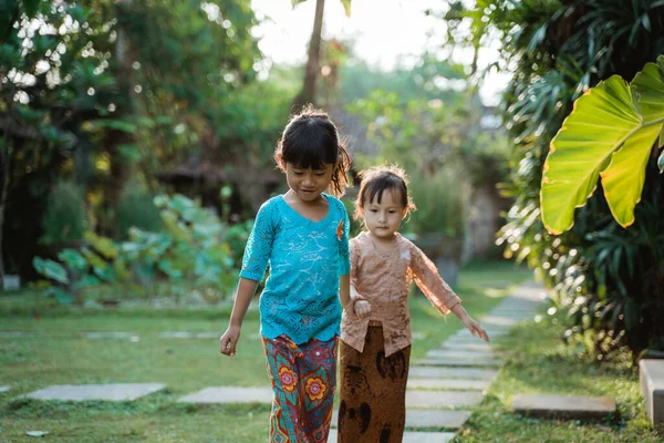 Glück zwei hübsche Mädchen in traditionellen javanischen Kebaya mit Händchen halten, wenn sie zusammen gehen — Stockfoto