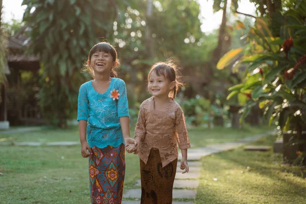 Dwie ładne dziewczyny w tradycyjnej kebaya javanese trzymając się za ręce podczas spaceru razem — Zdjęcie stockowe