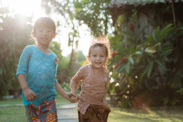 Duas menina bonita vestindo kebaya javanês tradicional com as mãos dadas quando correr — Fotografia de Stock