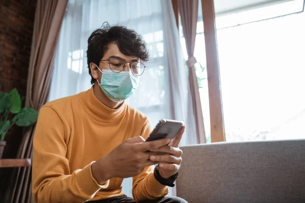 Homem usando máscaras médicas usando telefone celular durante o bloqueio epidêmico do vírus — Fotografia de Stock