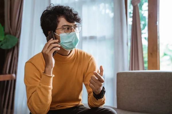 Homme portant des masques médicaux utilisant un téléphone portable pendant le verrouillage de l'épidémie de virus — Photo