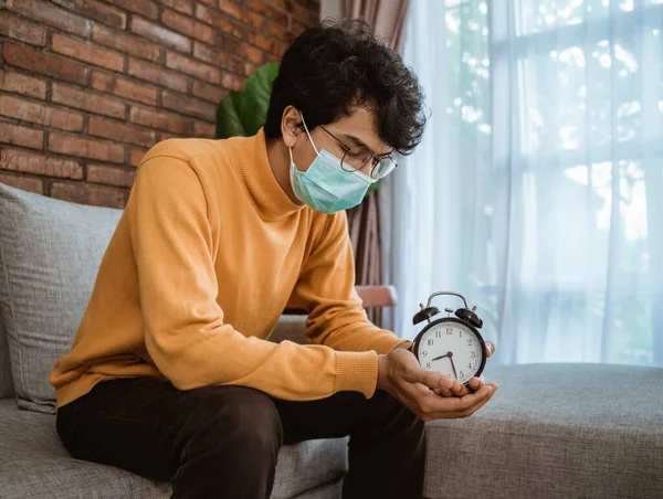 Homem com máscaras segurando um relógio de mesa — Fotografia de Stock