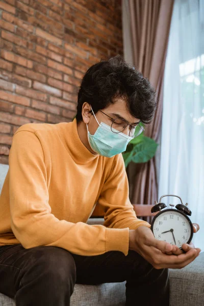 Homem com máscaras segurando um relógio de mesa — Fotografia de Stock