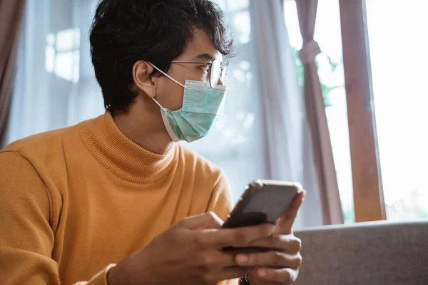 Homem usando telefone e máscaras no rosto durante a pandemia — Fotografia de Stock