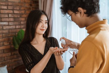 Kadın ve erkek el dezenfektanı kullanıyor.