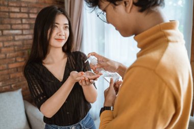 Kadın ve erkek el dezenfektanı kullanıyor.