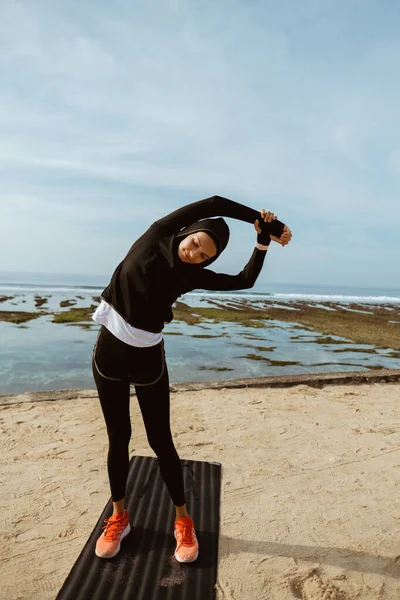 Mujer deportista musulmana en la playa haciendo ejercicio —  Fotos de Stock