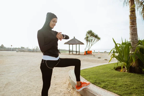 ジョギング前にスマートウォッチを設定するイスラム教徒の女性 — ストック写真