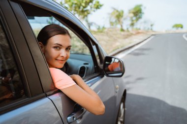 Kadın arabasında otururken gülümsüyor.