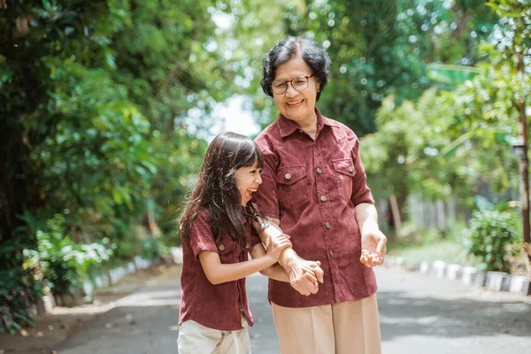 Nenek dengan cucu bercanda ketika berjalan bersama-sama — Stok Foto