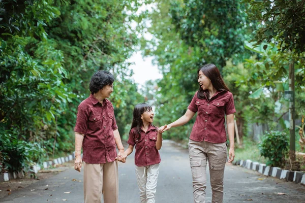 Having fun daughter, mother and grandmother joking and holding hands while enjoying walk in the park — Stock Photo, Image