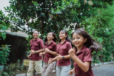 Asyalı aile dışarı koşuyor, gülümsüyor ve eğleniyor.