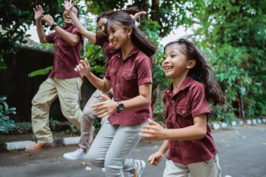 Asyalı aile dışarı koşuyor, gülümsüyor ve eğleniyor.