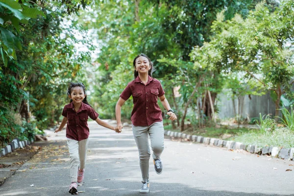 Asiatiska systrar springer utomhus håller händer och ler — Stockfoto