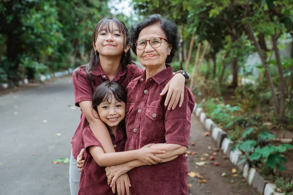 Две азиатские внучки обнимают свою бабушку — стоковое фото