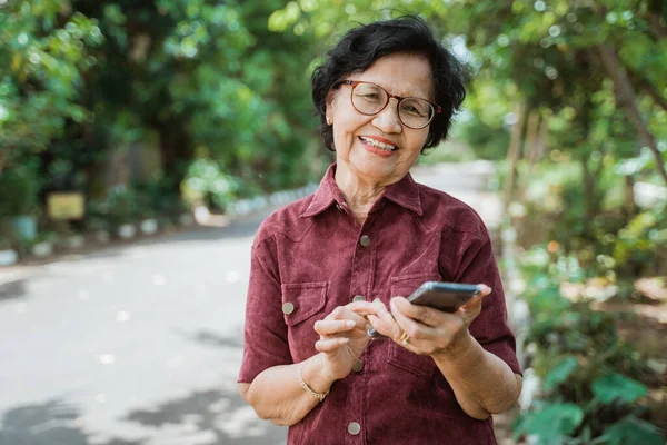 Sourire asiatique vieille femme à l'aide d'un téléphone cellulaire — Photo