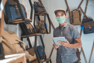 Asyalı erkek işletme sahibi tablet ile bir çanta dükkanda