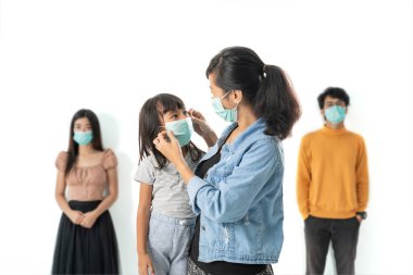 Yüz maskesi takan hasta bir kadın ve kızı var.