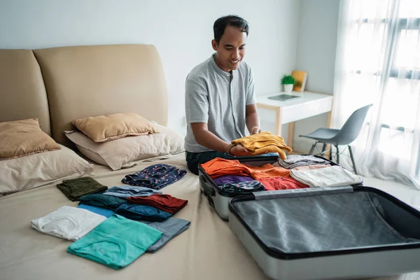 Ázsiai férfi teszi a ruháit a bőröndbe — Stock Fotó