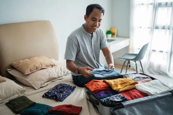 Jovem preparando suas roupas colocar na mala — Fotografia de Stock