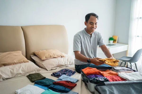 Ásia homem colocando seu roupa no o mala — Fotografia de Stock