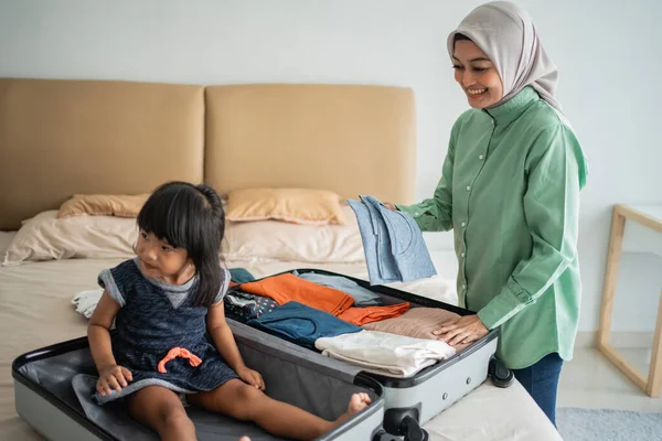 Anya ruhákat készít, és a lánya játszik a bőröndjével. — Stock Fotó