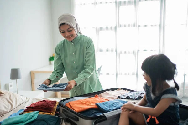 Mãe prepara roupas e sua filha brinca com sua mala — Fotografia de Stock