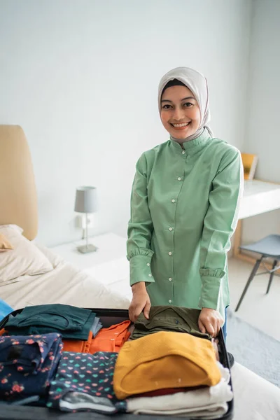 A hidzsábot viselő muszlim nők ruhát készítenek a bőröndbe rakáshoz. — Stock Fotó