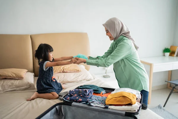 Η κόρη δίνει ρούχα στη μητέρα της όταν ετοιμάζει ρούχα. — Φωτογραφία Αρχείου