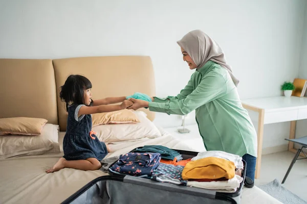 Tochter gibt ihrer Mutter Kleidung, wenn sie Kleidung zubereitet — Stockfoto