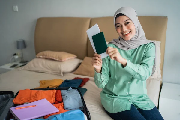 Asiatische muslimische Frau lächelt mit einem Ticket nach der Vorbereitung ihrer Kleidung — Stockfoto