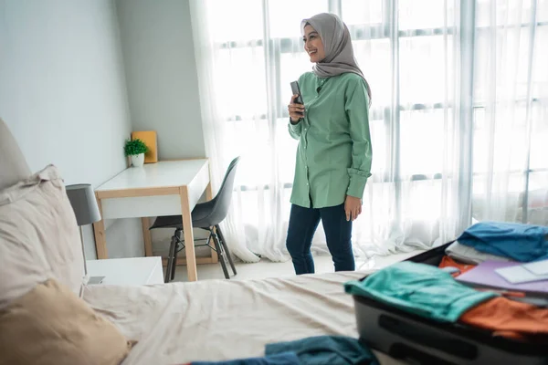 Asian muslim woman looking horarios de salida vía teléfono móvil — Foto de Stock