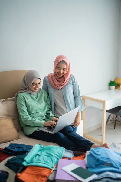 Zwei muslimische Frauen suchen per Online-Anwendung per Laptop nach Abflugplänen — Stockfoto
