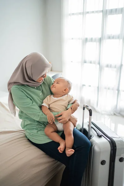 Ibu Muslim membawa bayi mereka sambil duduk di tempat tidur — Stok Foto