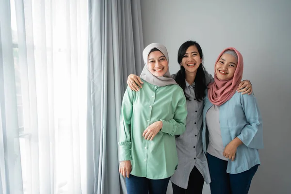 Persahabatan dari tiga wanita tersenyum berdiri di samping jendela — Stok Foto