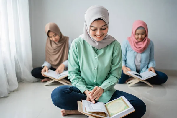 Trois jeunes femmes portant des hijabs lisent le livre sacré du Coran — Photo