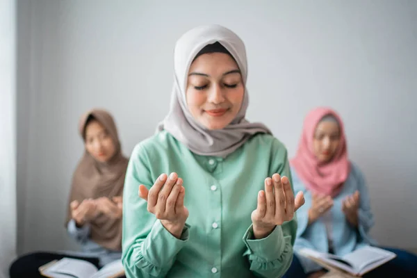 Drie gesluierde vrouwen zitten op de vloer te bidden — Stockfoto